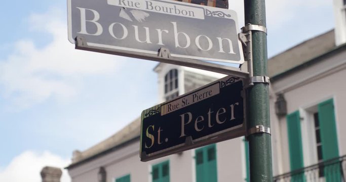 New Orleans Street sign at the corner of Bourbon and St. Peter with NOLA Decor in the background as they move in slow motion.