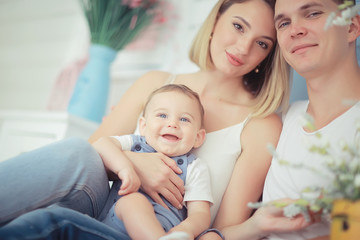 baby with parents in a cozy house / healthy young family mom dad and baby, happiness smile