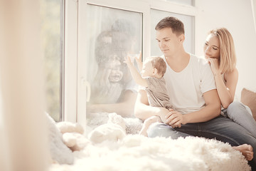 mom dad and baby little toddler sitting on the window / young family in a new apartment, beautiful housing