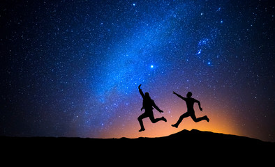Two men jumping one night with stars