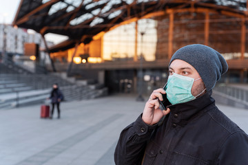 Portrait of man in face mask talking on phone on airport and protect health while coronavirus nad pandemic. Public transport and travel while covid19 and emidemic.