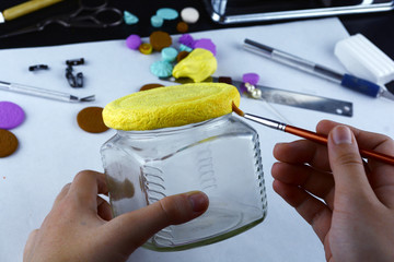 Handmade. Woman's hands tint a clay cover on a jar on the white background. Clay sculpting process, art.