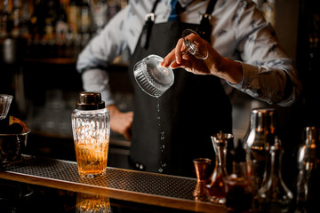 Fototapeta na wymiar man at bar prepares glass for cocktail.