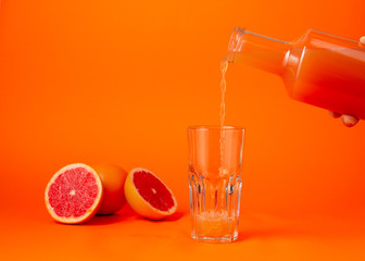 Pouring the grape juice in the glass over orange gradient background