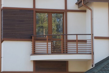 one brown open balcony with a glass door and a window on the gray wall of a private house