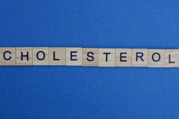 word cholesterol from small gray wooden letters lies on a blue background