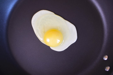 One egg frying on the hot pan, top view