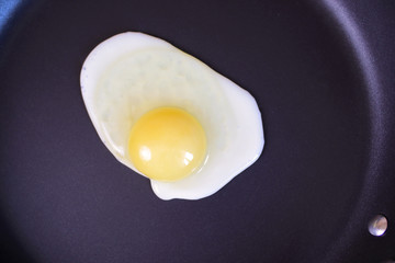 One egg frying on the hot pan, top view