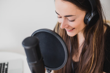 Woman blogger recording radio podcast in studio.