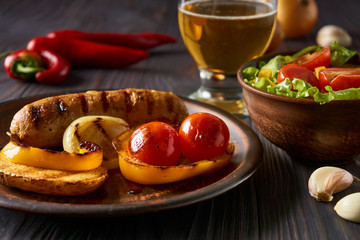 Chicken sausage with vegetables and light beer on a clay plate
