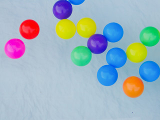 Many colored rubber balls float on the water.