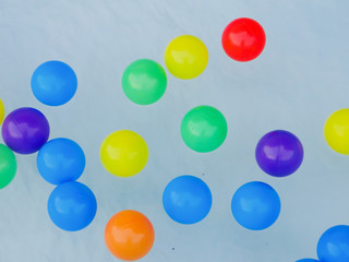 Many colored rubber balls float on the water.