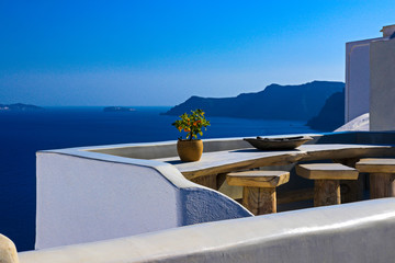 im Fokus steht ein kleines Orangenb&auml;umchen auf einem Holztisch an einer h&ouml;lzernen Bar mit Blick auf das Meer