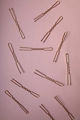 Golden hair clips on pastel pink background. Top view.