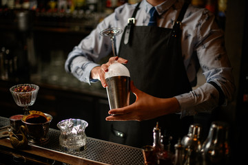 bartender in black apron preparing to make cocktail.