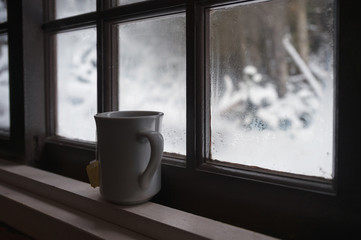 White teacup on window sill in snowing day