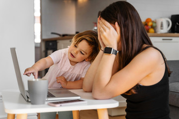 Mother working from home with baby toddler. Crying child and stressed woman. Stay home