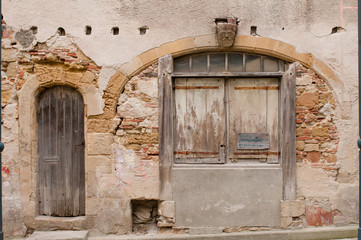 Fachada de casa antigua de piedra con arcos y busto