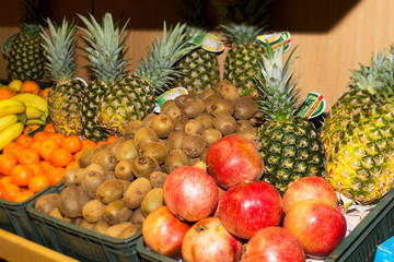 Fruit on a shelf in the market. Bananas, oranges, lemons, strawberries, apples, pineapples, kiwi are presented.