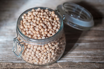 Raw chickpeas in a glass jar on an old wooden Board. Healthy vegan product