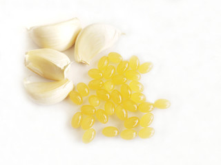 Garlic  supplement capsules and garlic cloves on white background with copy space. Selective focus at the capsules. 