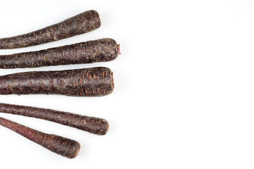 Fancy colorful vegetables. Set of purple unpeeled carrots on light background. Copy space