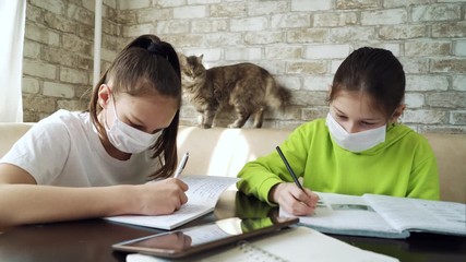Girls in medical masks staying on quarantine and doing homework