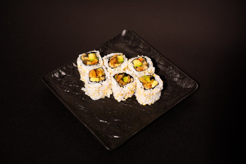 Set of six sushi on a black plate and on a black background