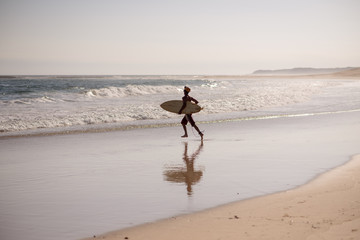 Surfer running towards water with his board