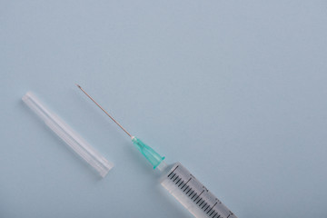 jeringuilla en diagonal sobre un fondo azul pastel con espacio