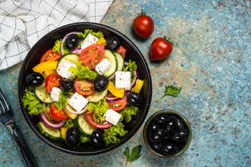 Greek salad in black plate on the table.