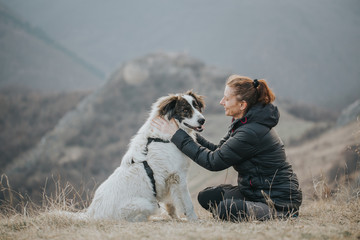 Young woman tourist hugging her dog outdoors while hiking with her best friend. 