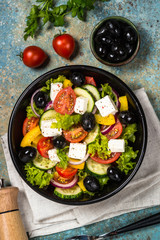 Greek salad in black plate on the table.