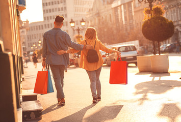 Smiling young couple walking at city street enjoying shopping together.