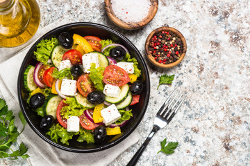 Greek salad in black plate on the table.