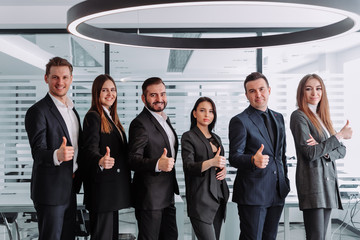 Business leaders with a group of employees showing their thumbs up