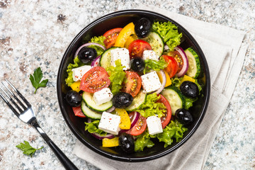 Greek salad in black plate on the table.