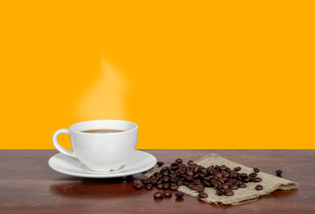 Coffee and coffee beans on a wooden table and an orange background.