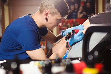 Tattoo artist creating a tattoo on a man's arm.