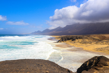ein wunderschöner Strand an der Westküste in Cofete mit Wolken die in den Bergen hängen
