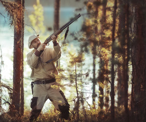 Naklejka premium hunting man / hunter with a gun hunting in the autumn forest, yellow trees landscape in the taiga