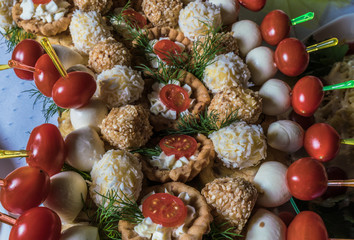 a variety of cold snacks on the table at parties; stuffed baskets, cheese balls, little tomatoes and more