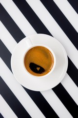 White ceramic cup of strong coffee on striped background. Morning coffee in minimalism
