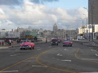 Havana,Cuba - January 25, 2020 : A classic american car rides along the seaside Malecon avenue in Havana with the Capitol building on the background
