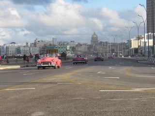 Havana,Cuba - January 25, 2020 : A classic american car rides along the seaside Malecon avenue in Havana with the Capitol building on the background
