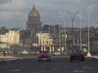 Havana,Cuba - January 25, 2020 : A classic american car rides along the seaside Malecon avenue in Havana with the Capitol building on the background