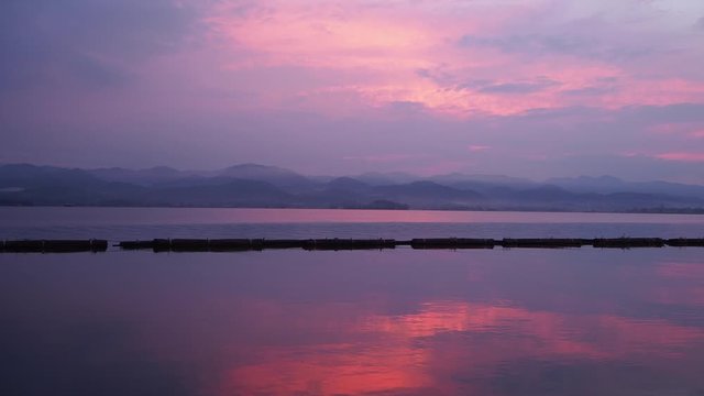 Beautiful colorful vibrant sunrise at dam with purple and orange clouds in the blue sky reflected in the silky water bellow.