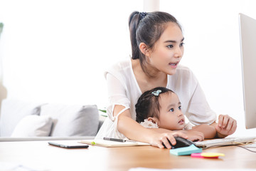 Asian mother watching her daughter who is learning to use the computer. Mom and kids, education, family relationship, child care, technology for children concept.