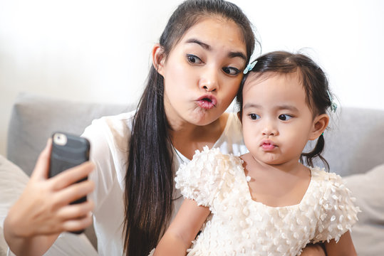Asian mother are using cell phones take selfie photo with her daughter. The love of a mother with a daughter.