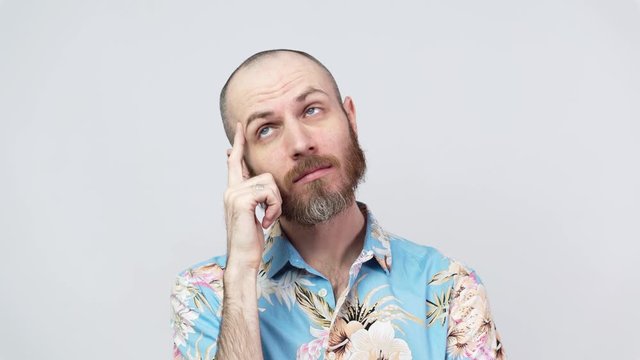 Portrait of a man wearing hawaiian shirt thinking or remembering, isolated over white background. Concept of emotions.
